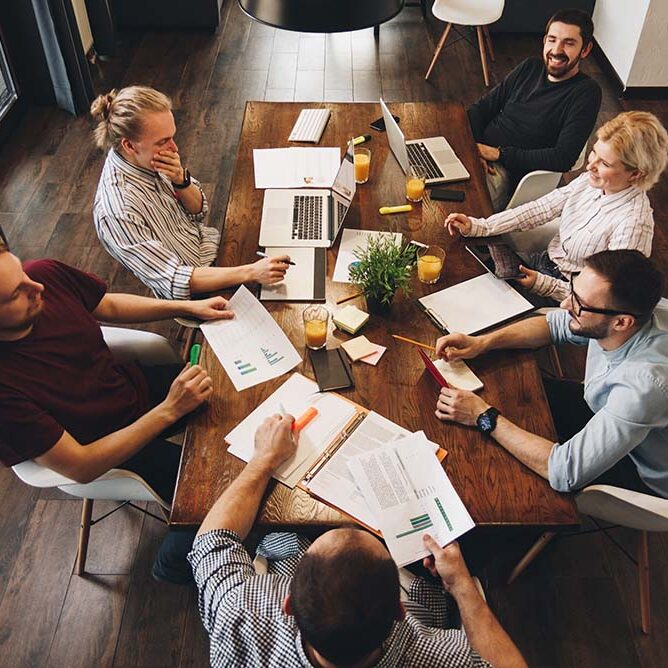 Photo on top of group of young business team working together on new project. Teamwork of creative managers in loft space. Concept of work in modern office on laptops and tablets